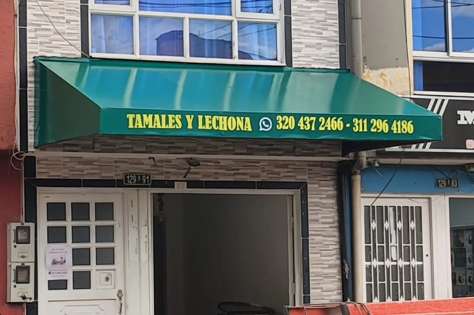 Toldo fijo de lona verde con la razón social y los teléfonos impresos, instalado sobre la fachada de un local comercial